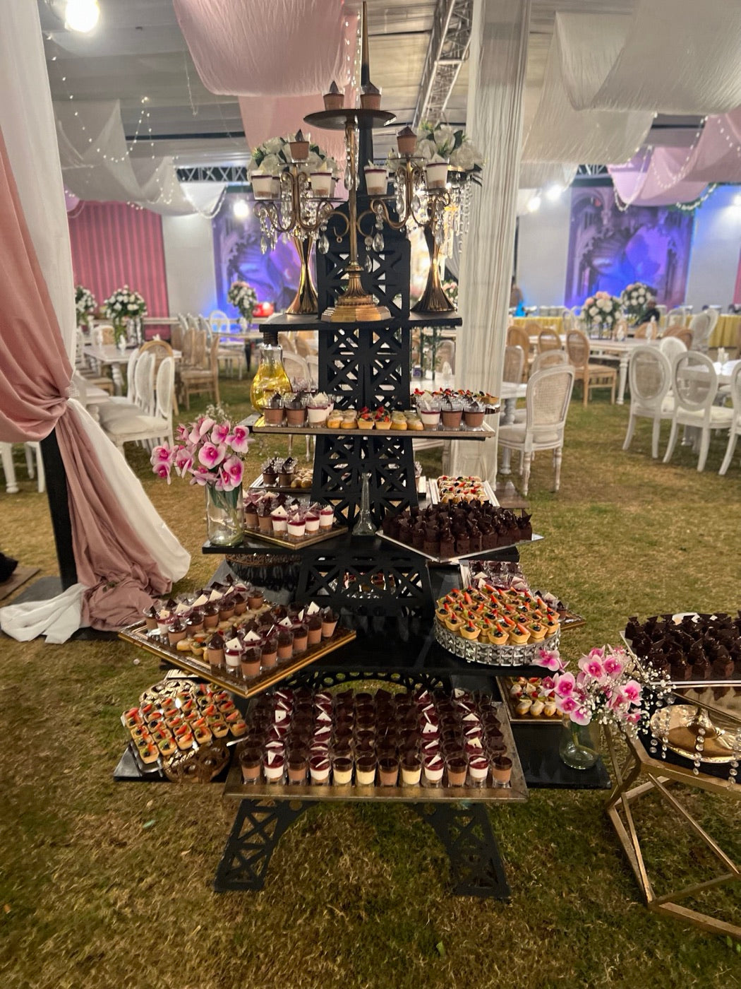 An outdoor Coco 9 dessert table: shooters and tarts on a tall black tower stand under draped fabric